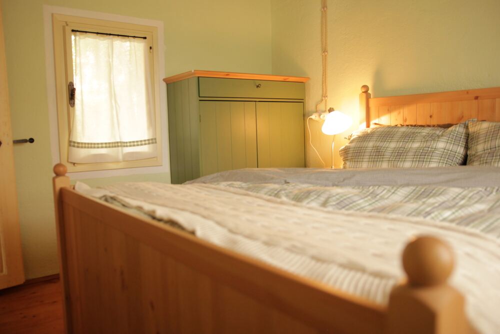 Camera verde con armadio in legno e letto matrimoniale